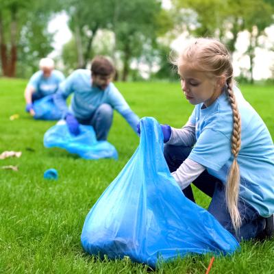 School girl with group of eco volunteers picking up litter park, saving nature.jpeg